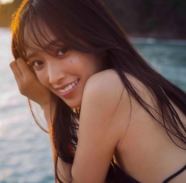 ⽇向坂46 佐々⽊久美1st写真集 「めくる⽇々」大人っぽい黒のサテンドレスを纏い、水上コテージのデッキでサンセットタイムに撮影しました。けやき坂46、そして日向坂46の初代キャプテンとしてチームを支え、引っ張ってきた佐々木久美さん。 | MAYA